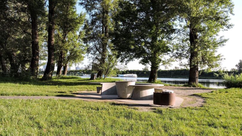 copyright: Wiener Gewässer Grillplatz mit Tisch und Sitzelementen aus Beton inmitten von Wiese auf der Wiener Donauinsel