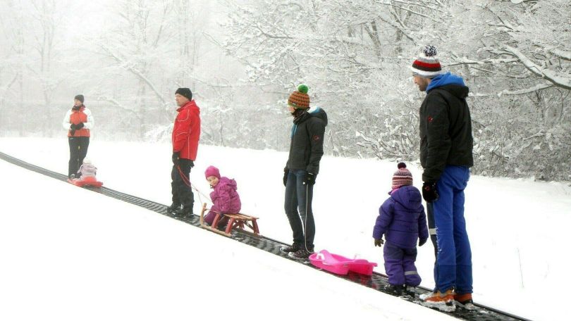 copyright: Stadt Wien / Martin Votava Kinder und Eltern mit Bobs und Schlitten auf einem Schlitten-Förderband