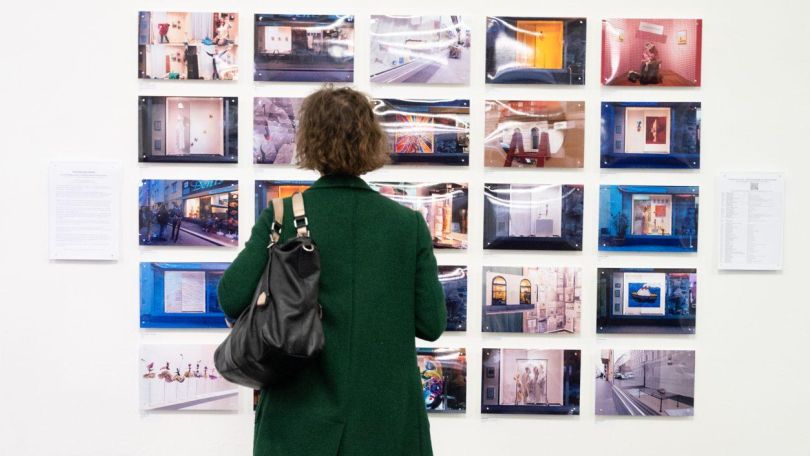 copyright: Daniel Shaked Eine Frau betrachtet Fotografien an einer Wand.