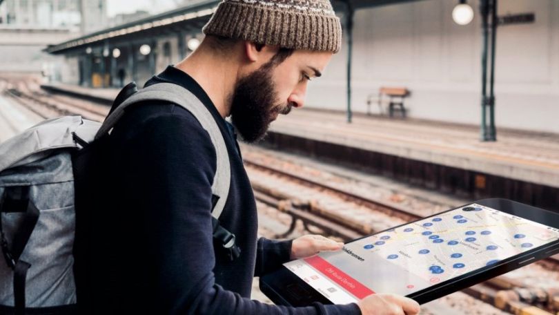 Mann mit übergroßem Handy steht auf U-Bahn-Steig