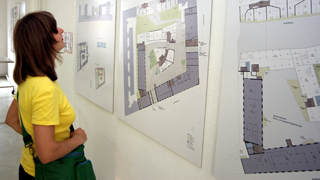 Frau betrachtet Gebudeplan in einer Architekturausstellung