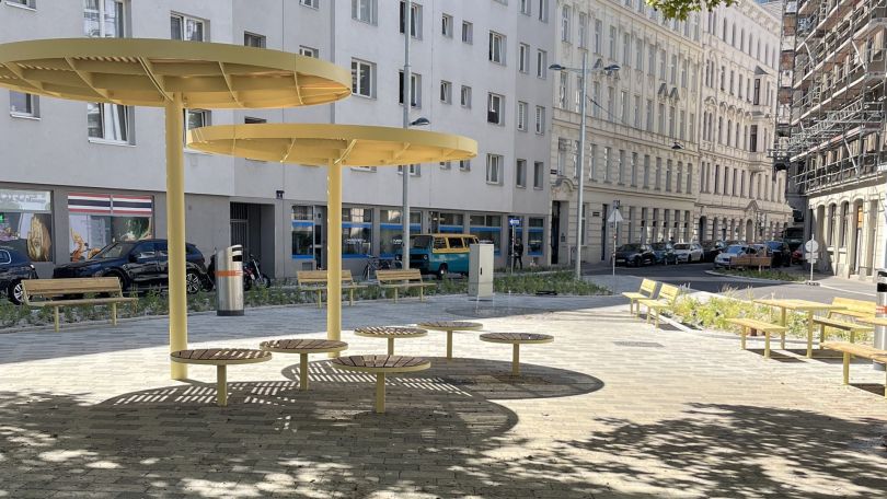 copyright: BV 2 Der neu gestaltete Czerninplatz mit heller Pflasterung mit vielen Bänken und Pflanzenbeete rundherum; In der Mitte sind runde Sitzgelegenheiten mit Beschattung; Ein Baum wirft viel Schatten auf den Platz