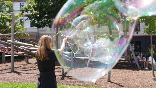 Mädchen macht Riesenseifenblasen in einem Park
