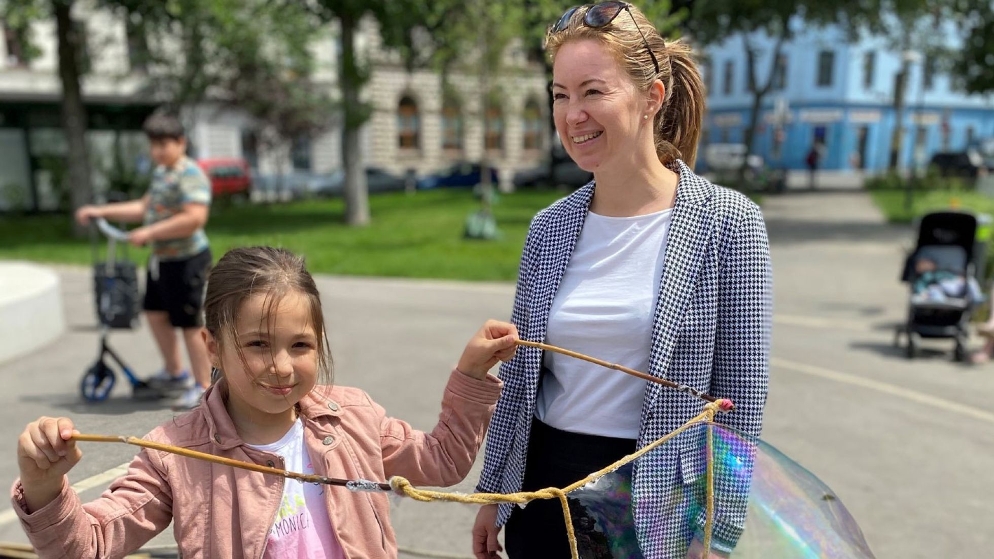 Silvia Jankovic steht neben einem Mädchen, welches große Seifenblasen produziert