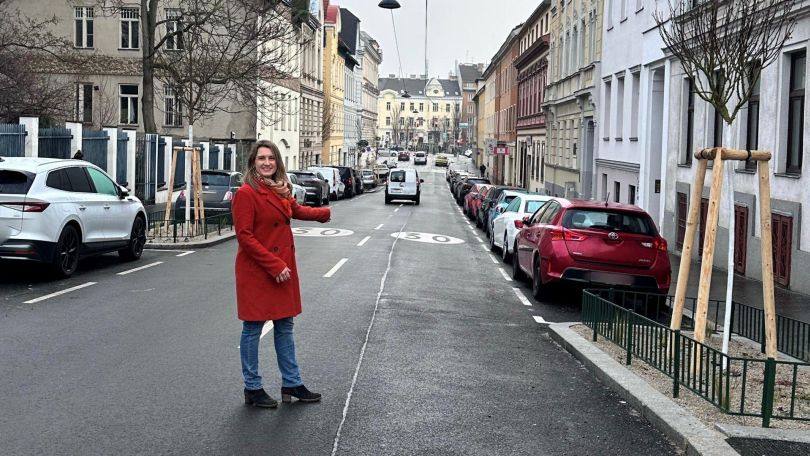 copyright: BV 13 Frau im roten Mantel auf einer neu asphaltierten Straße mit Tempo-Bodenmarkierung "30".