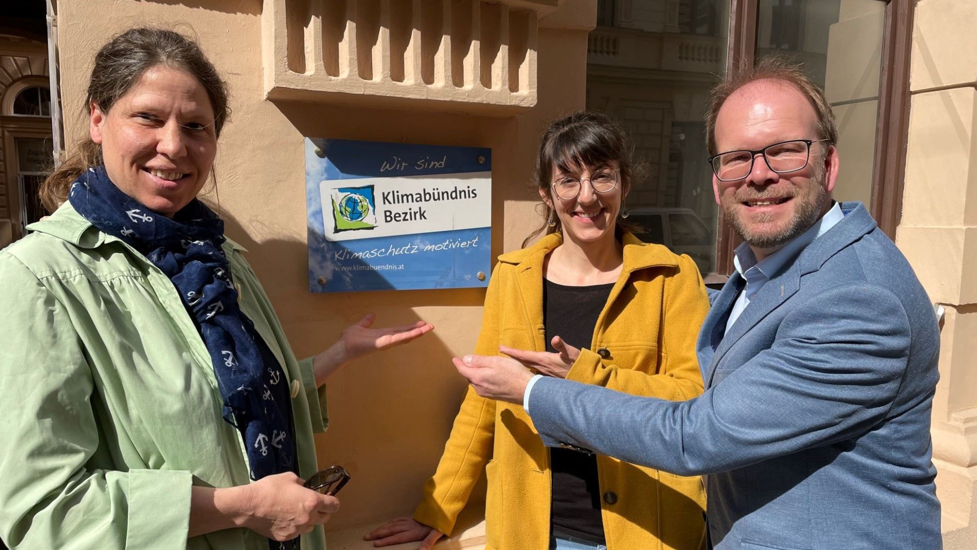 copyright: BV 15 2 Frauen und 1 Mann zeigen auf eine Plakette mit der Aufschrift "Klimabündnis Bezirk"