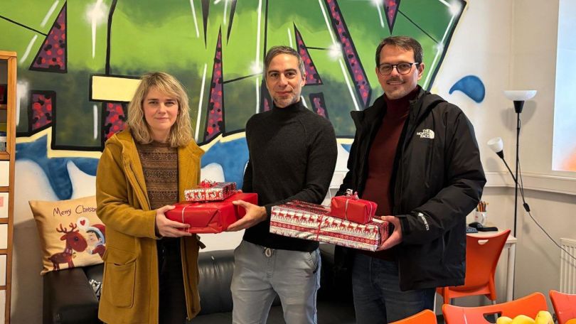 copyright: BV 16 Eine Frau und 2 Männer halten Weihnachtsgeschenke.