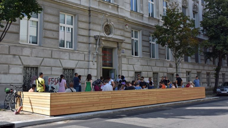 Altbau mit hölzernem Tor und Holz-Zaun zur Straße hin