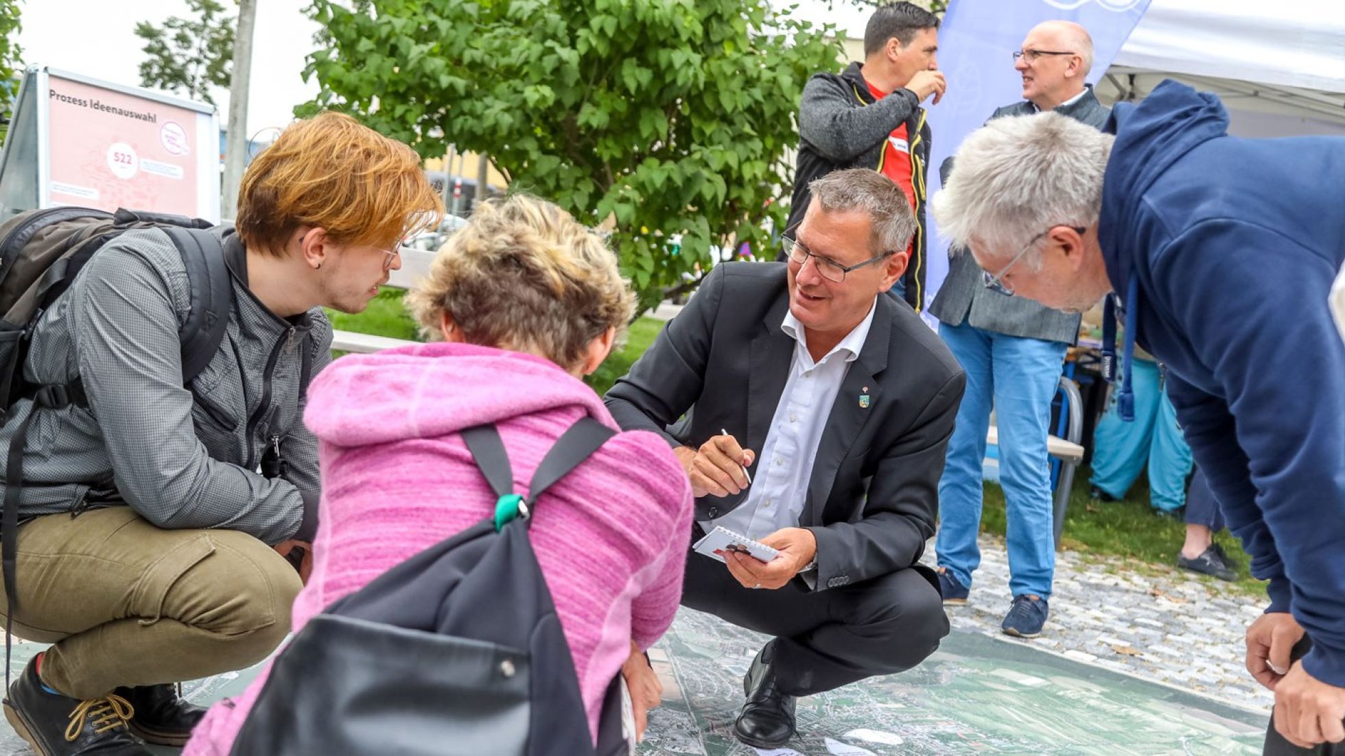 copyright: MA20/Christian Fürthner Georg Papai hockt mit 2 Personen im Freien am Boden und bespricht Beteiligungsprojekt