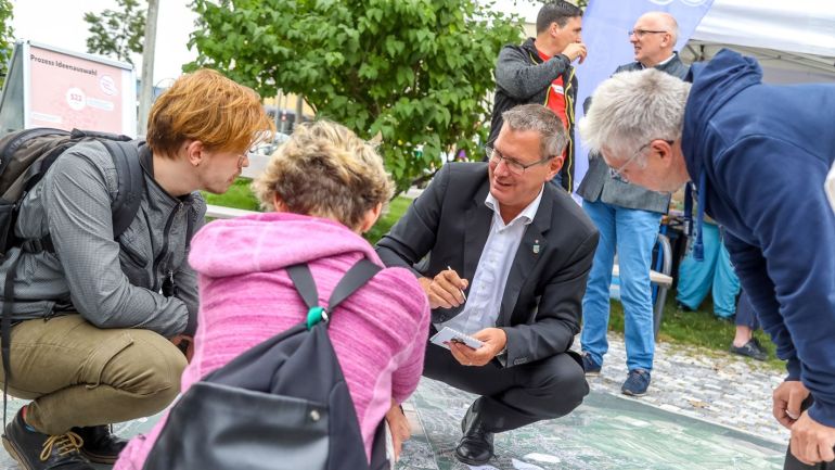 copyright: MA20/Christian Fürthner Georg Papai hockt mit 2 Personen im Freien am Boden und bespricht Beteiligungsprojekt