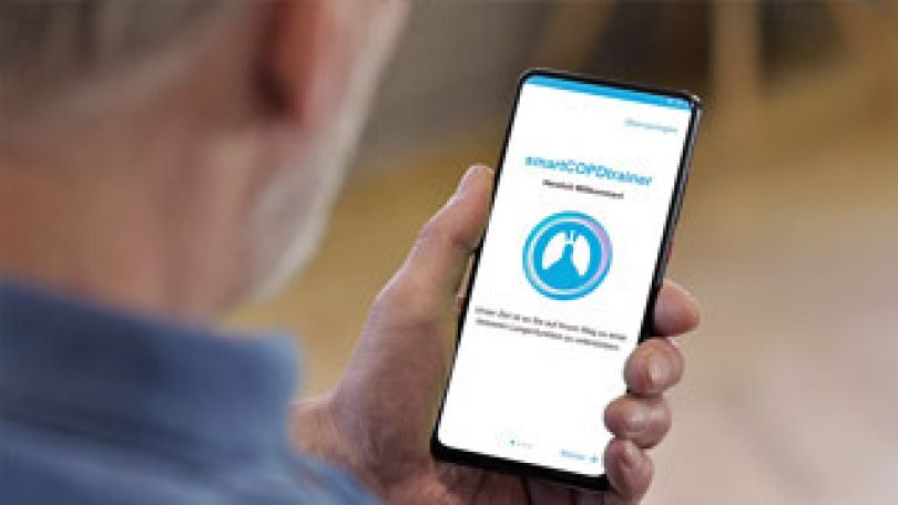 copyright: KODYM Gerhard Ein älterer Mann hält ein Handy in der Hand und ruft die COPD App auf