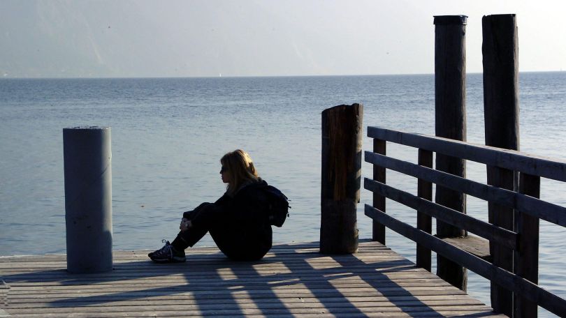 copyright: Bilderbox.com Eine Frau sitz alleine auf einem Steg am Wasser
