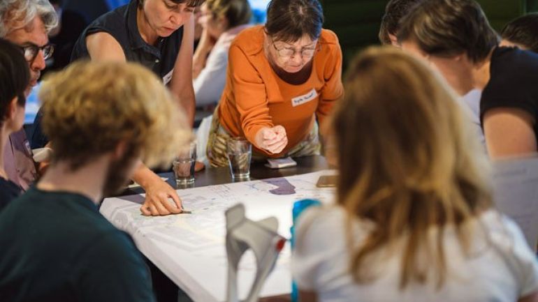 copyright: BV 6 Daniel Dutkowski Menschen rund um einen Tisch beugen sich über einen Straßenplan und diskutieren Potentiale für eine Umgestaltung des öffentlichen Raums