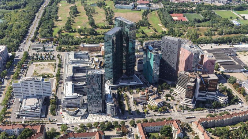 copyright: Stadt Wien / Christian Fürthner Mehrere Hochhäuser mit Glasfassade, eine Straße führt rundherum, im Hintergrund sind Bäume und Wiesen