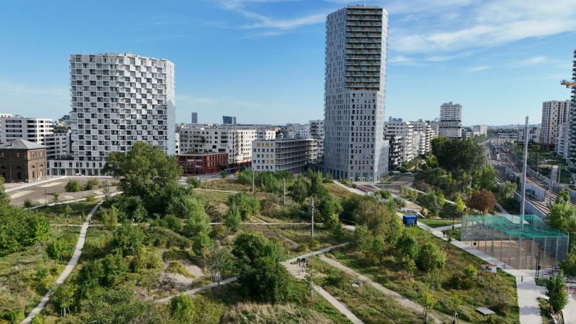 copyright: Stadt Wien/Petra Dworzak 2 höhere Gebäude, dazwischen etwas niedrigere, davor ein grüner Park mit Wegen.