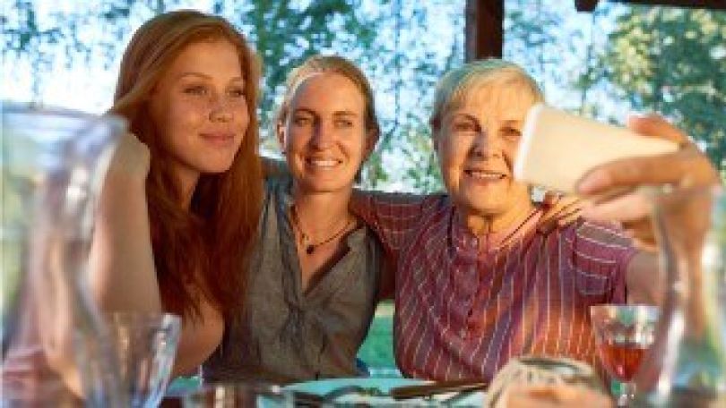 copyright: MA 24 3 Frauen sitzen an einem Tisch, legen sich Arm um Schulter, die Älteste macht mit dem Handy ein Gruppen-Selfie