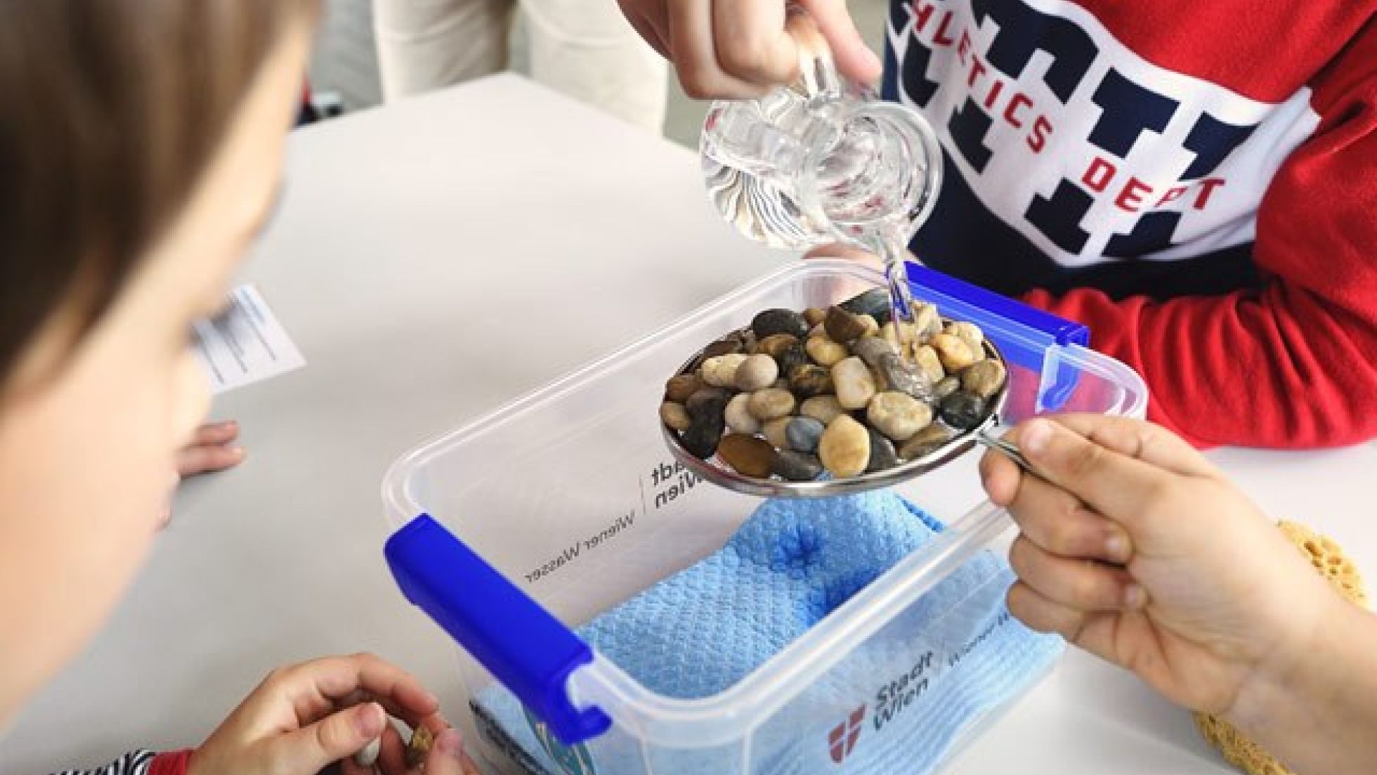 copyright: MA31 / Johannes Zinner Schüler leert Wasser über einen Teller voller Steine