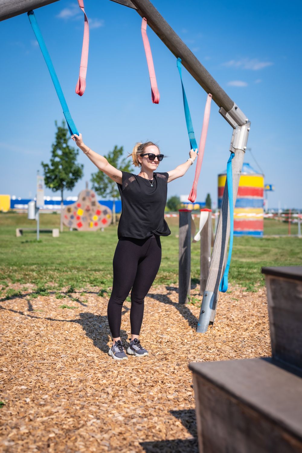 Motorikpark Eine Frau dehnt ihre Arme an Seilen.