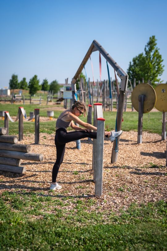copyright: David Bohmann Eine Frau dehnt ihr Bein an einem Holzgerät.