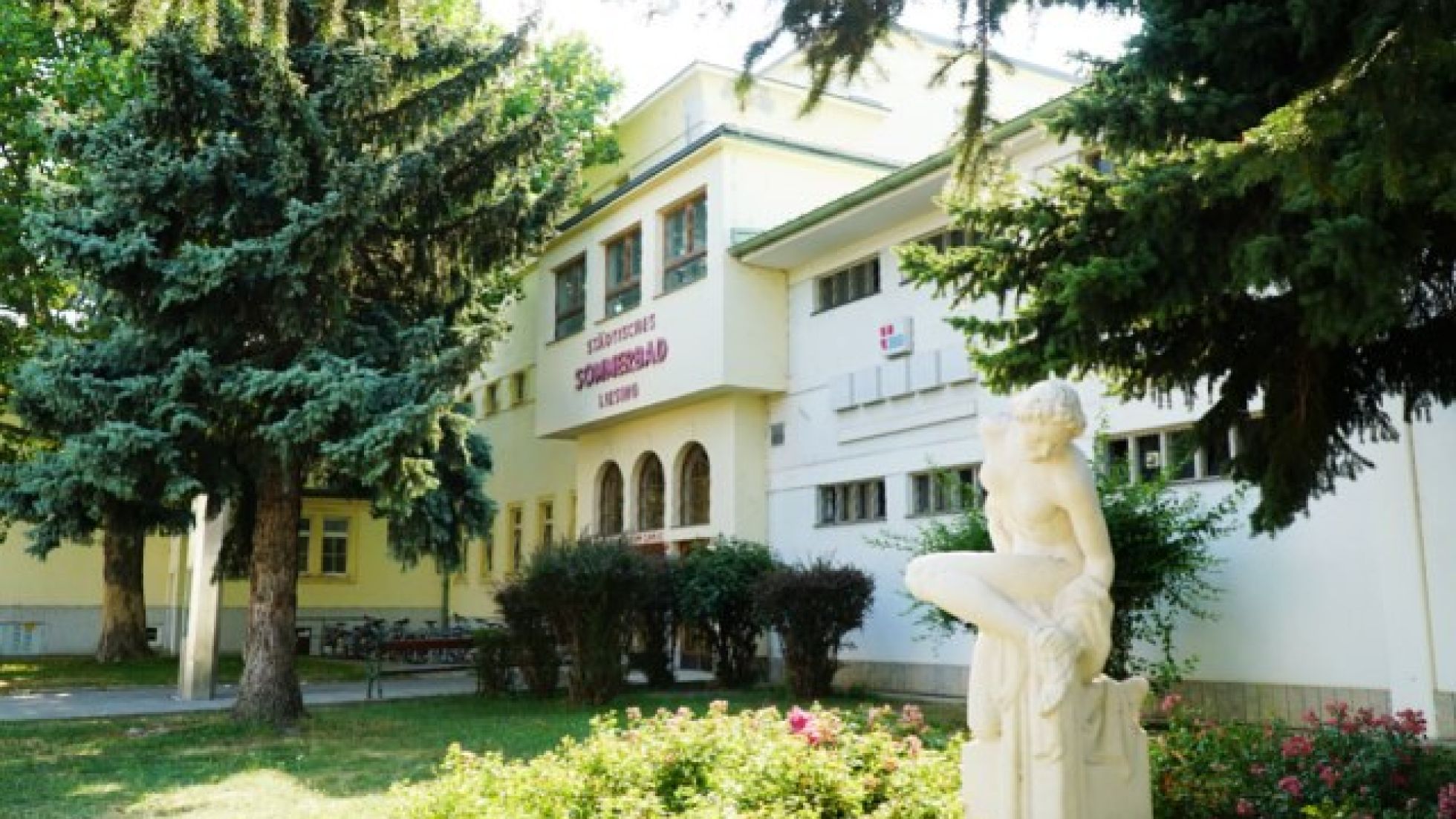 copyright: Stadt Wien/Horst Lassnig Eingangsbereich des Liesinger Bad mit einer Statue und Bäumen