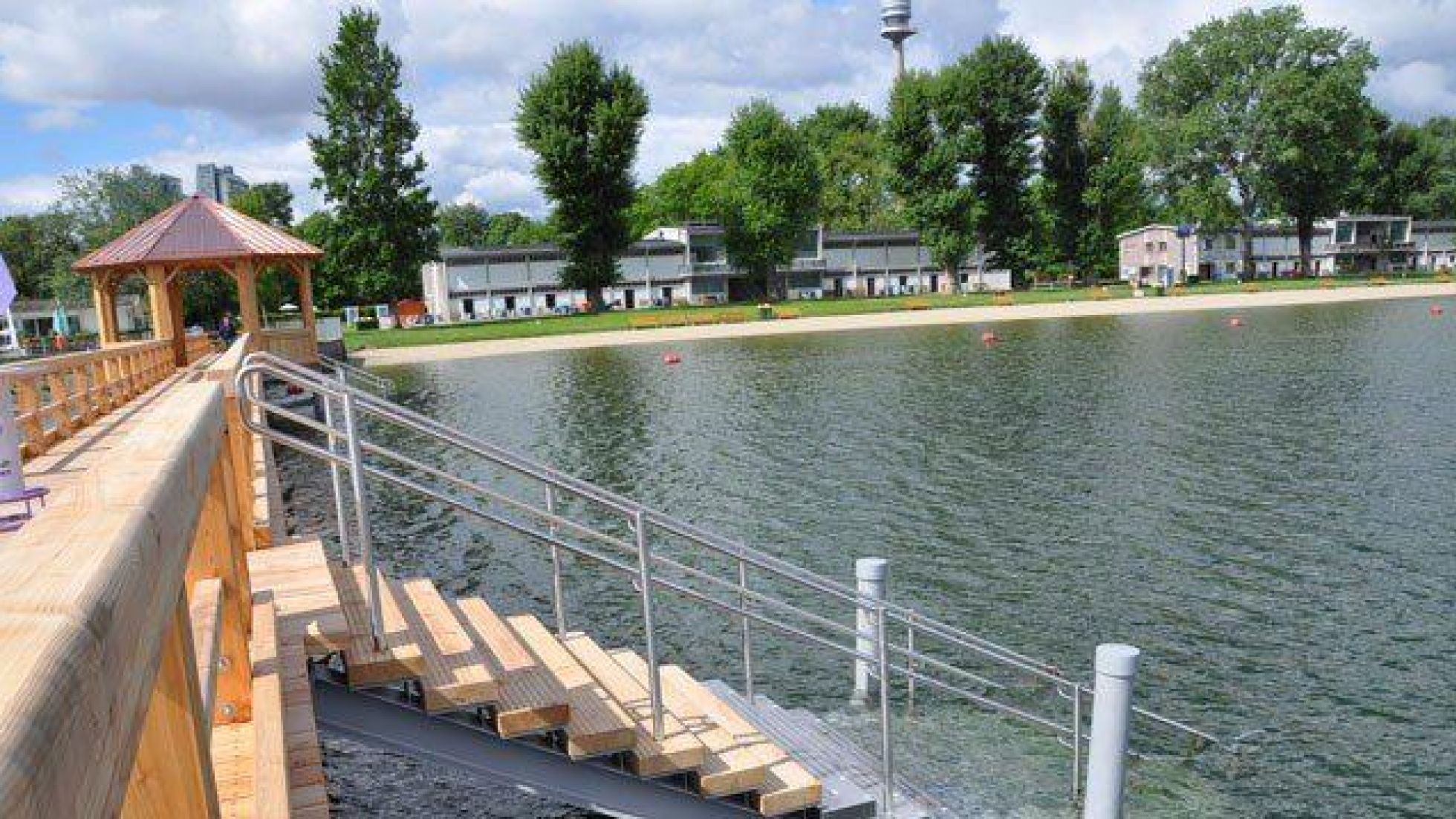copyright: Stadt Wien - Bäder (MA 44) Vom Steg führen Stufen ins Wasser, im Hintergrund ist die Liegewiese am Ufer der Alten Donau zu sehen.