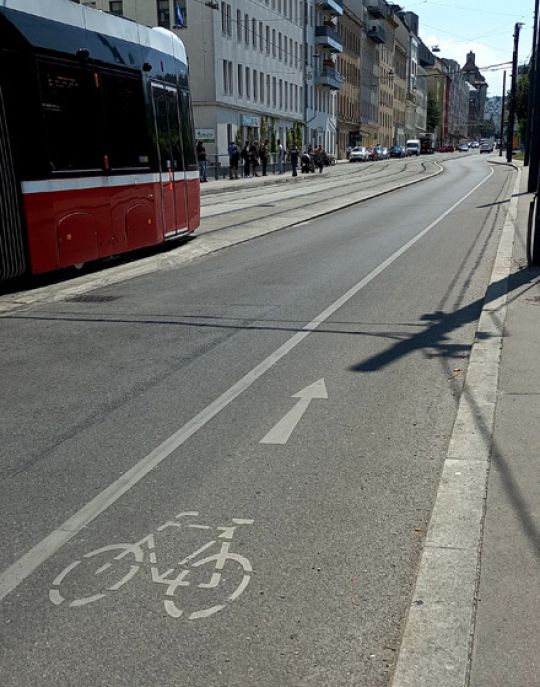 copyright: MA 46 Der Radfahrstreifen ist von der restlichen Fahrbahn durch eine Trennlinie getrennt. In der Mitte der Straße fährt eine Straßenbahn.