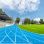 copyright: Architekturfotografiewien / Romana Fürnkranz Outdoor-Sportanlage mit blauer Laufbahn, grünem Rasen in der Mitte und einer Tribüne am Rand der Bahn.