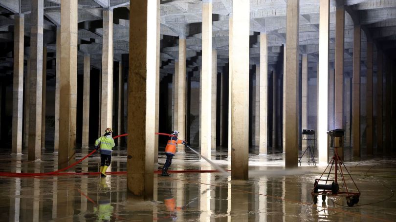 copyright: Stadt Wien/Martin Votava Großer unterirdischer Wasserbehälter aus Beton mit Säulen und Mitarbeitern, die mit Wasserschlauch arbeiten.