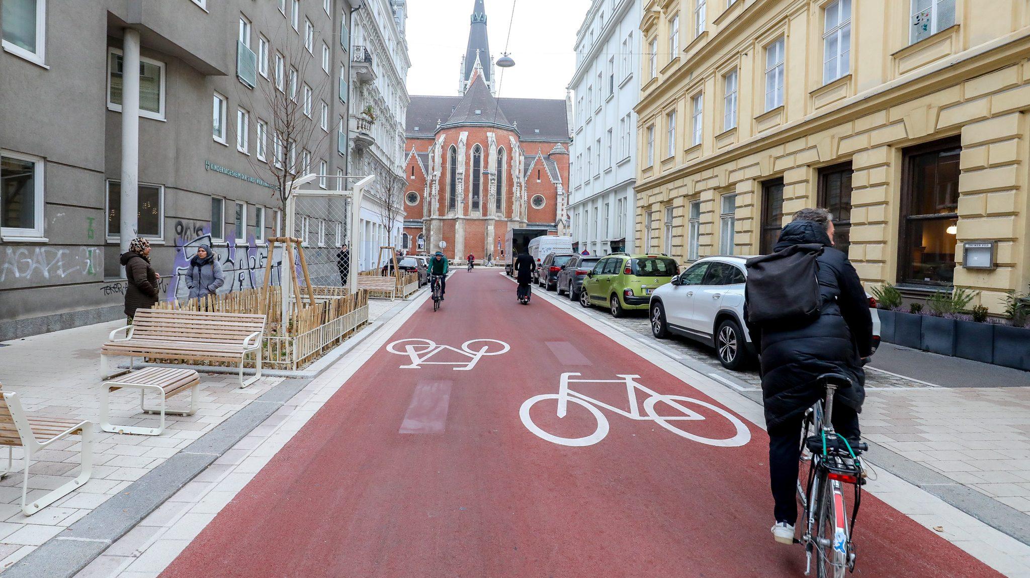 Radfahrende auf einer breiten Fahrradstraße mit rotem Belag