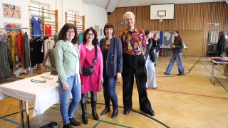 3 Frauen und 1 Mann in einem Turnsaal bei einem Verkaufstisch