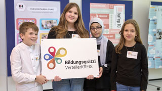 4 Schler*innen halten ein Schild mit Schriftzug "Bildungsgrtzl VerteilerKREIS"