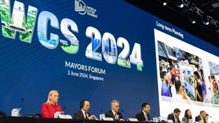 Teilnehmer*innen des World Cities Summit Mayors Forum 2024 sitzen an einem langen Pult mit Mikrofonen