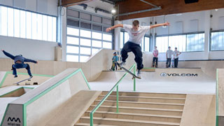 Jugendlicher mit Skateboard auf Stange