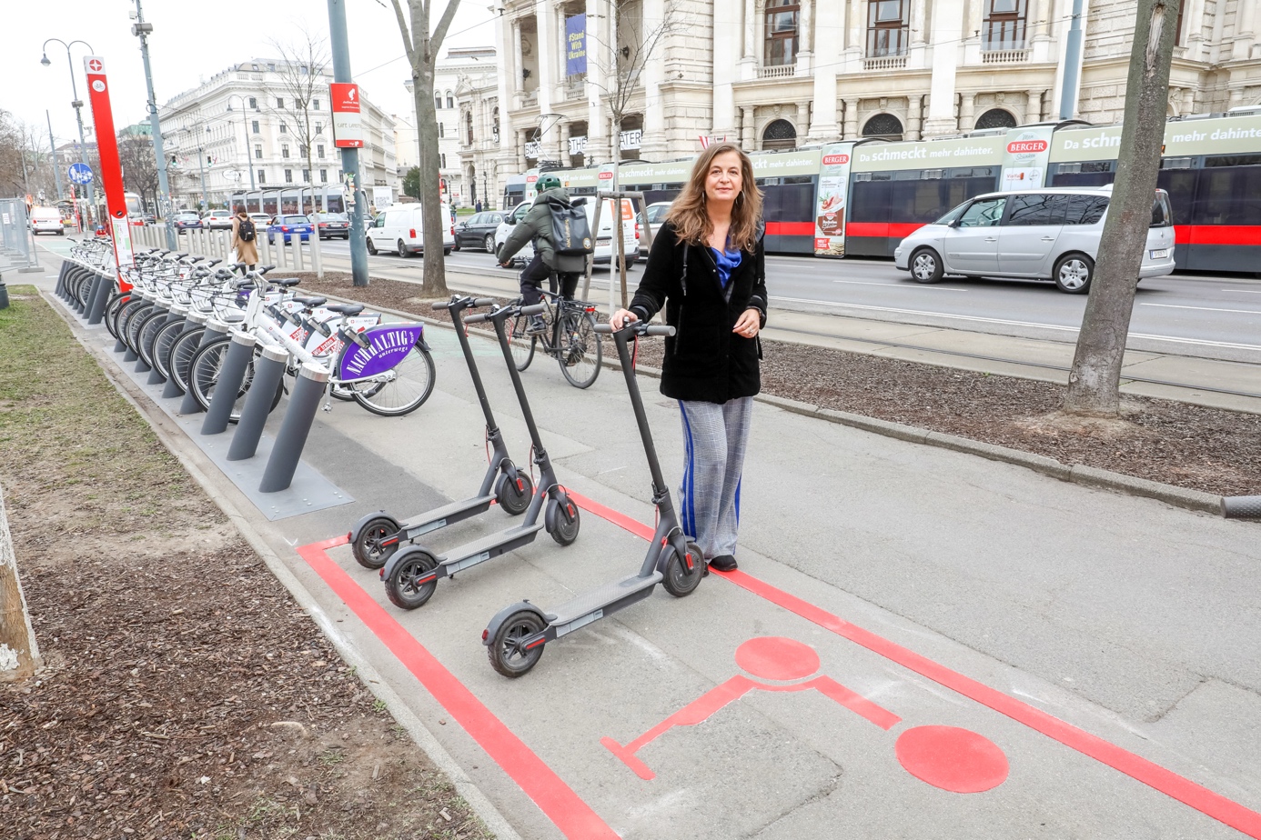 Uli Sima mit Scootern vor einem Scooterparkplatz