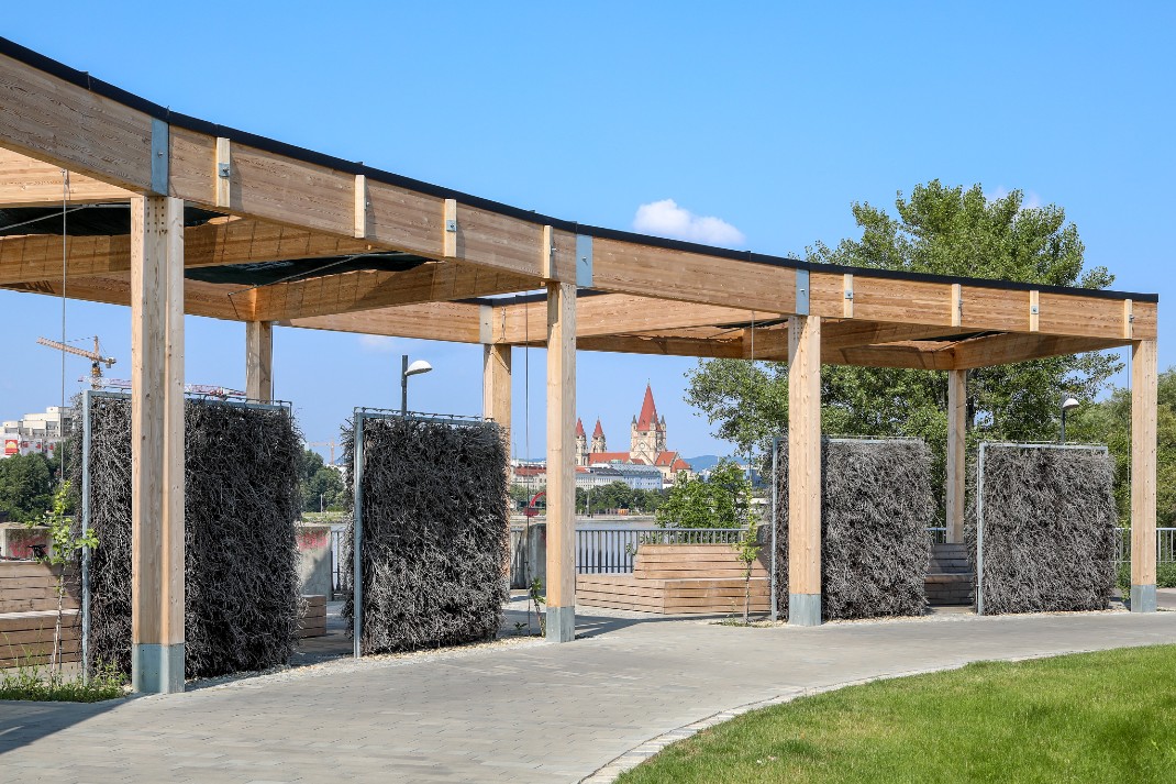 Im Halbkreis angeordnete Holz-Pergolen, darunter Gradierwände. Im Hintergrund Wien.
Copyright: Fürthner