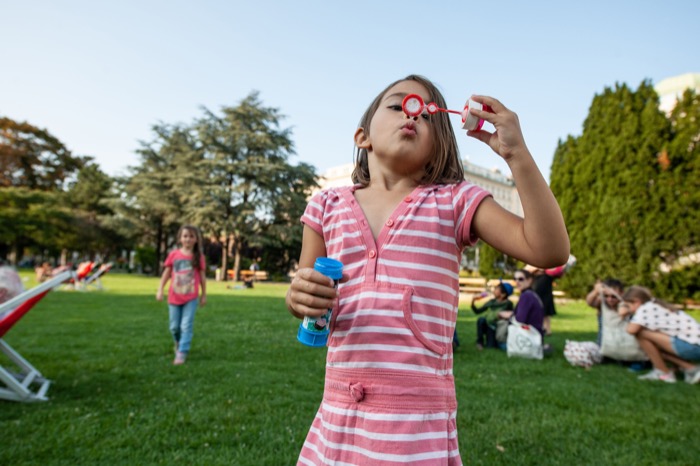 Mädchen bläst Seifenblasen im Rathauspark