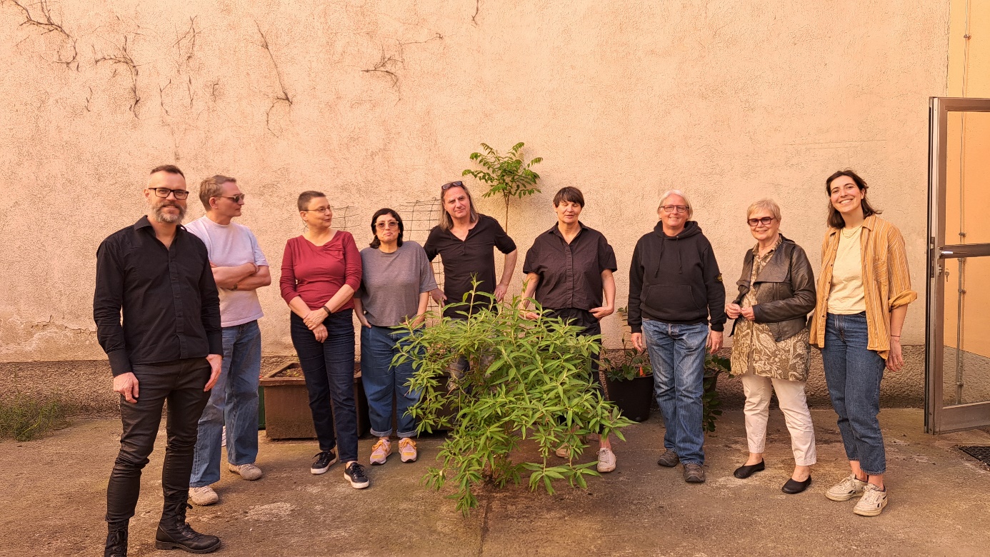 Group photo Van-der-Nüll-Gasse 20

Group photo of eight artists and Helene Scheller (far right) standing in a semicircle around a shrub