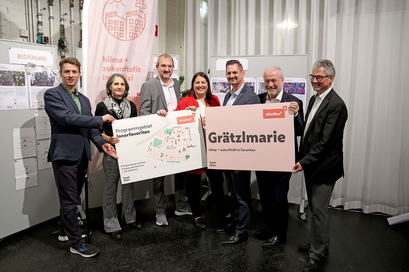 Final “Grätzlmarie” presentation 

Group photo of seven persons; from left to right: Stephan Hartmann, Andrea Breitfuss, Otto Eckl, Kathrin Gaál, Marcus Franz, Gerhard Blöschl, Arthur Mannsbarth. Together, they are holding two large panels; the left shows the Innerfavoriten programme area and the right bears the "Grätzlmarie" slogan.