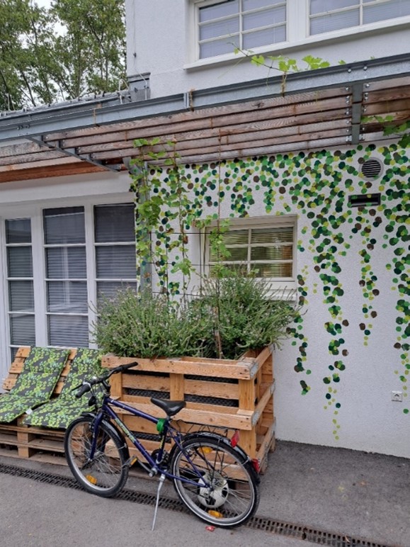 Gardening and cycling

A raised bed with seats and greenery and, right beside it, a parked bicycle, with the Arthaberbad youth centre in the background