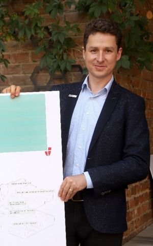 Stephan Hartmann, WieNeu+ Programme Manager

Photo of Stephan Hartmann, wearing a dark suit and light-coloured shirt and holding a large WieNeu+ poster, with a brick wall in the background