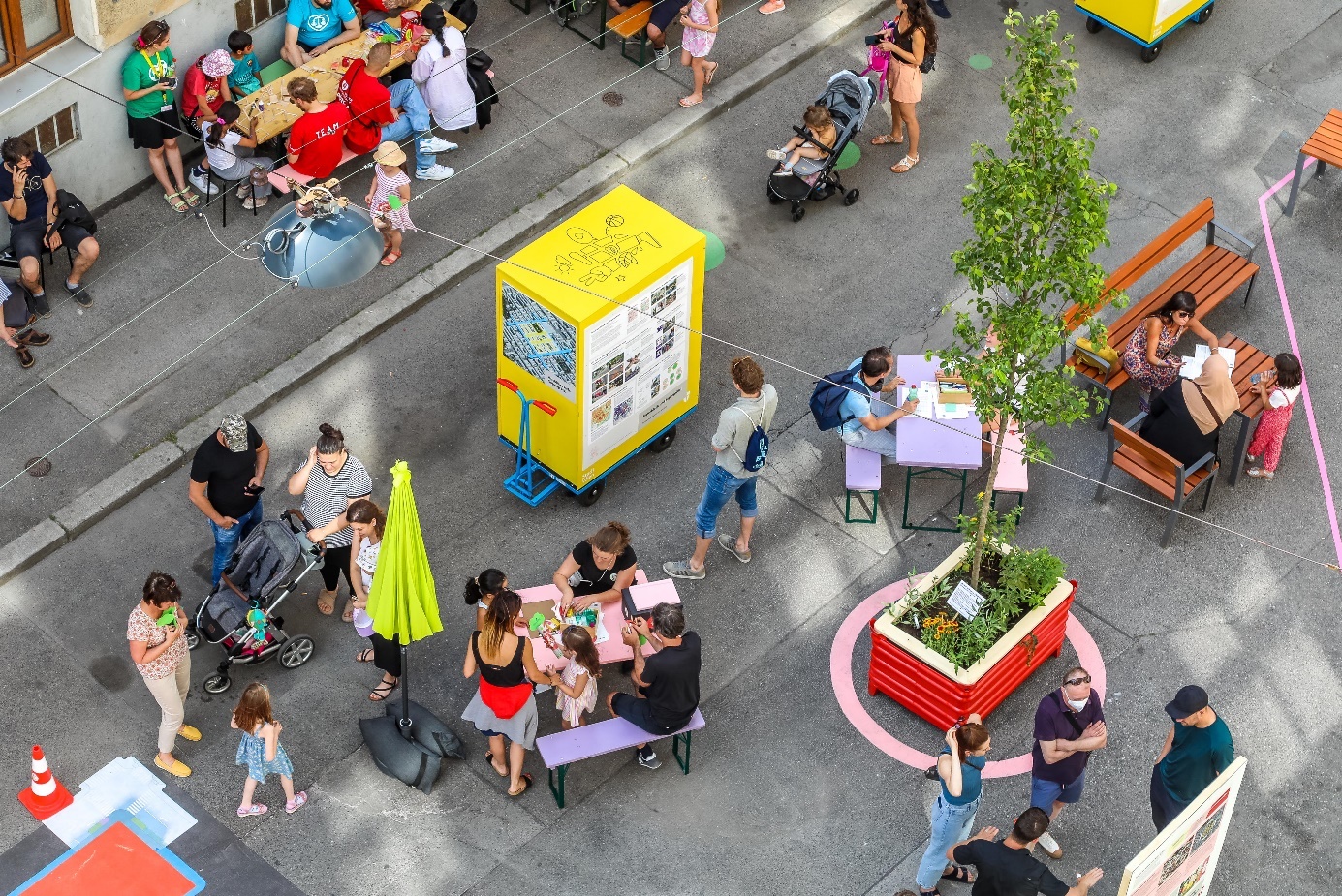 Supergrätzl information event shown from above

Street event with large-scale, colourful neighbourhood map, with children and adults playing on the ground 