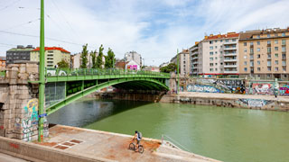 Grne Brcke aus Metall beim Donaukanal, dahinter Wohngebude