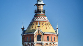 Turm in Backsteinbauweise mit buntem Ziegeldach